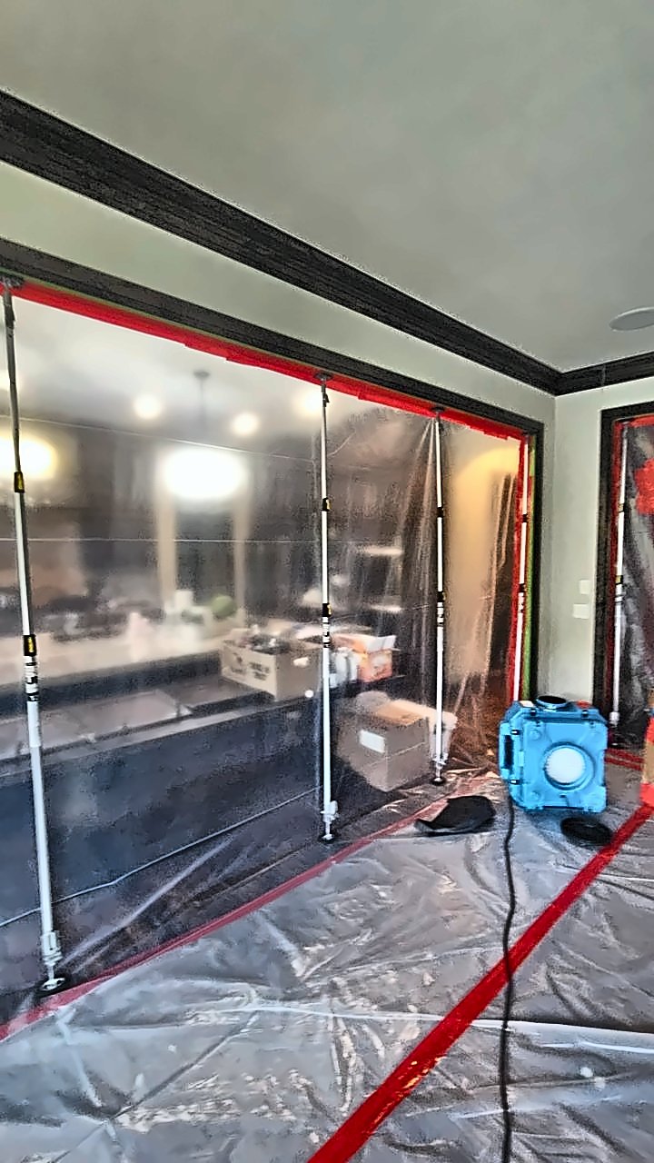 A floor-to-ceiling 4D Restoration containment wall splits an open room, with an air scrubber inside.