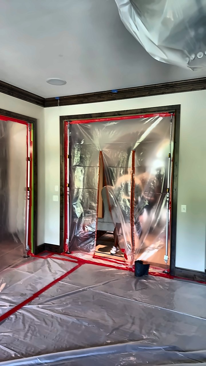 A room fully sheeted for containment by 4D Restoration — floor covered, doorways sealed with zip-wall barriers.