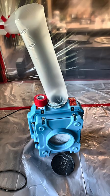 A HEPA air scrubber runs inside sealed containment on a 4D Restoration structural drying job.