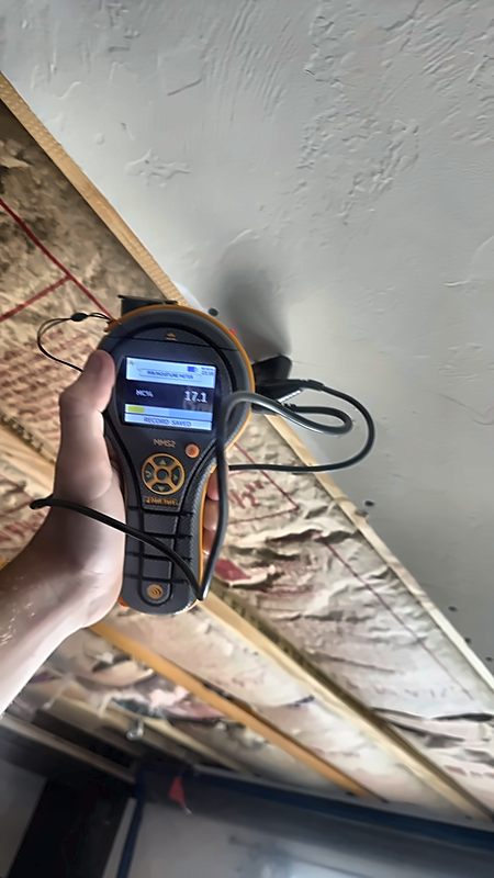 A moisture meter in a 4D Restoration tech's hand reads 17.1 percent against framing during an inspection.