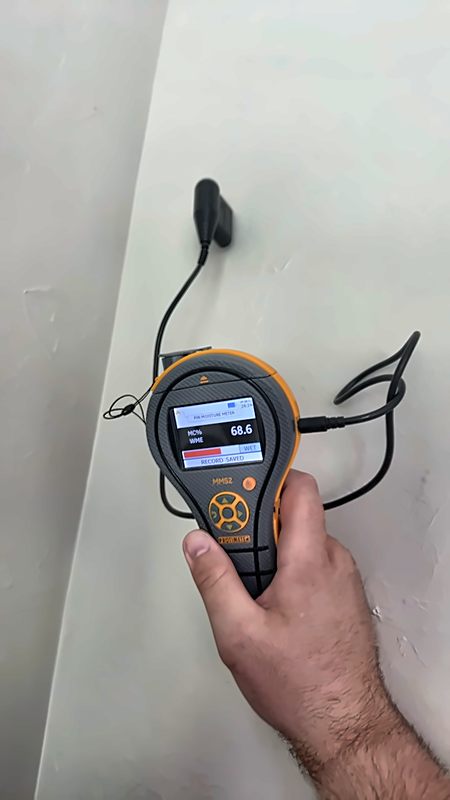 A Protimeter moisture meter reads 68.6 percent — wet — on a wall during a 4D Restoration assessment.