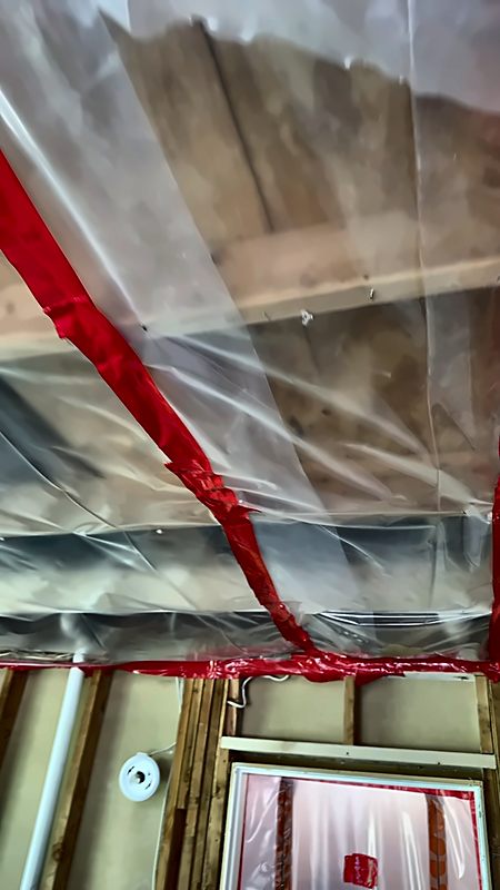 Clear sheeting taped to ceiling joists with red containment tape on a 4D Restoration mold job.
