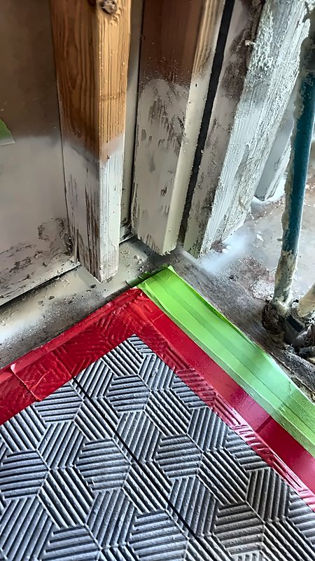 Taped floor protection laid at the base of exposed framing on a 4D Restoration job.