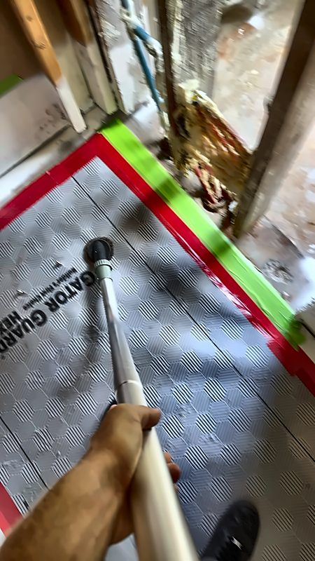 A 4D Restoration tech vacuums taped-down floor protection beside opened walls.