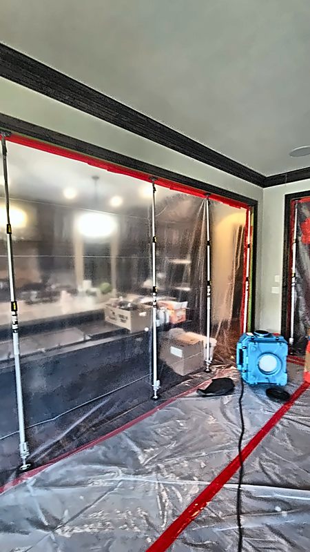 A floor-to-ceiling 4D Restoration containment wall splits an open room, with an air scrubber inside.