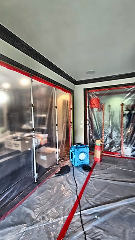 A 4D Restoration containment setup — sealed doorways, covered floor, and an air scrubber staged in the room.