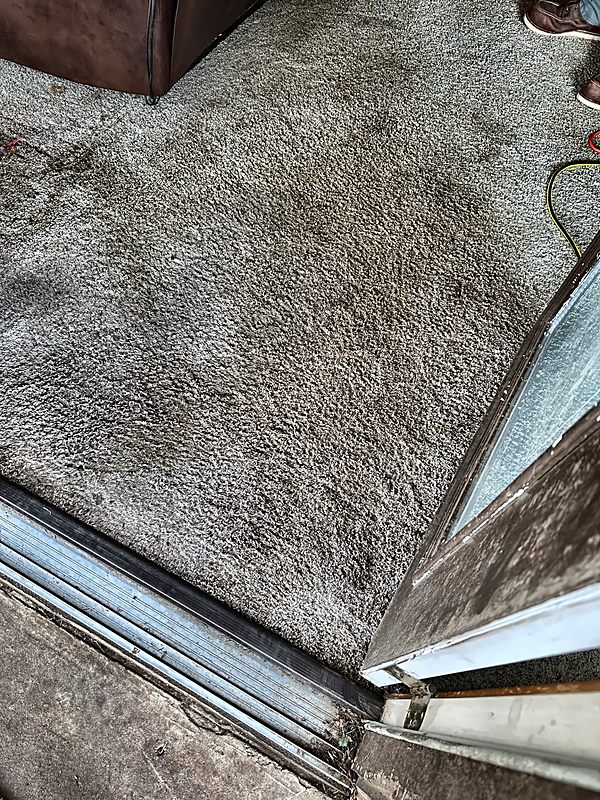 A dark saturation ring on carpet at a sliding-door threshold, documented on a 4D Restoration water call.